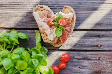 Healthy brown bread with ham, cheese and tomatoes on a wooden table.