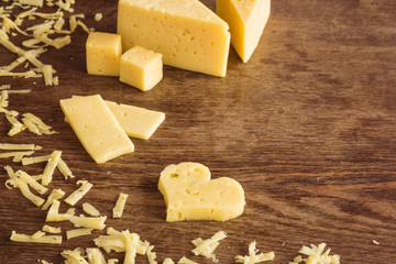 Cheese peaces on the old wooden table in the kitchen. Dairy product. Healthy eating and lifestyle.