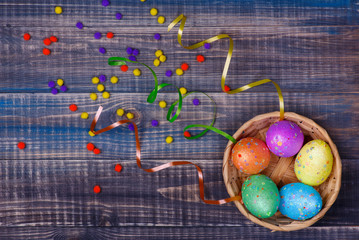 Top view of the Easter eggs lying in the basket. Basket with eggs is on a wooden table.