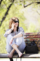 Young and trendy hipster woman sitting on a bench while speaking on her mobile. Lifestyle concept.