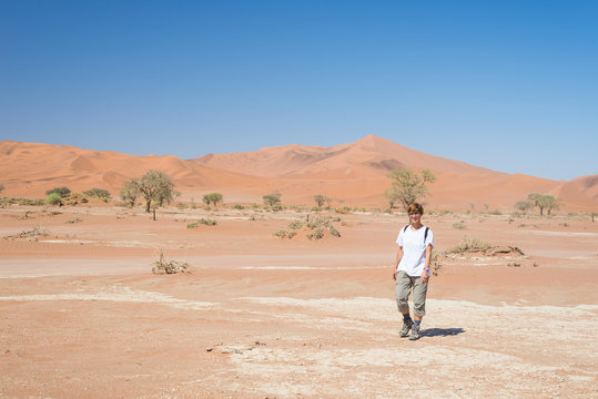 Tourist walking to Sossusvlei, Namib desert, Namib Naukluft National Park, scanic travel desetination in Namibia. Adventure and exploration in Africa.