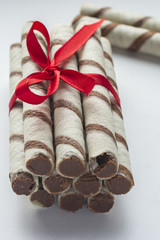 Chocolate sticks with red ribbon on white background