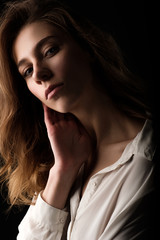 close up studio portrait of young woman in white blouse on black background