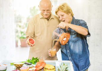 Happy senior couple preparing healthy vegetarian breakfast with fruits and vegetables