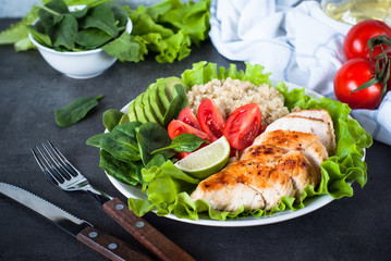 Fresh salad from quinoa, chicken breast, spinach, lettuce and tomatoes. Organic food. Healthy meal portion plate.