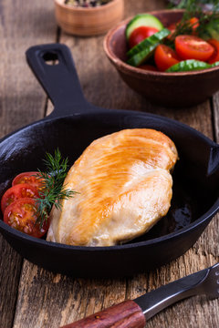 Fried chicken breast on skillet with tomatoes