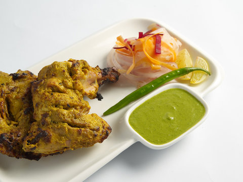 panch phoron chicken Bengali style with mint yogurt chutney served in a white plate