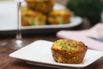 Nice and delicate broccoli savory cake served on white plate on a dark wood table. Good way to eat broccoli without knowing it.
