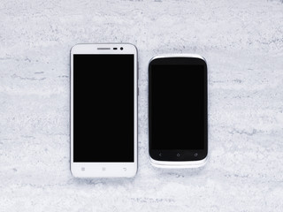Two white smartphones on grey background. Top view. Flat lay 