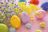 Colorful Easter eggs and spring flowers on rustic pink wooden background.