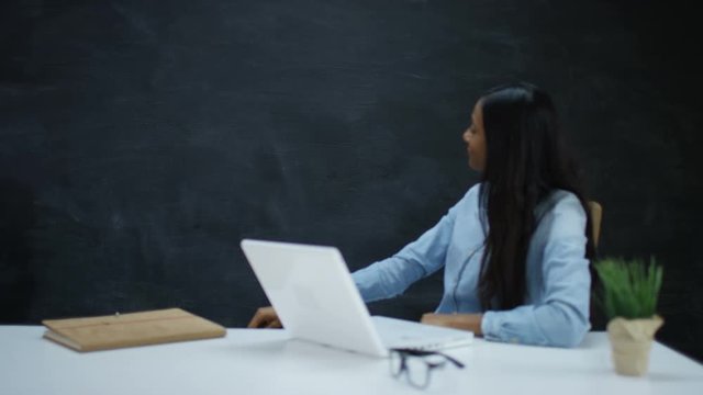  Woman with laptop moving her hand as if underlining a word on chalkboard 