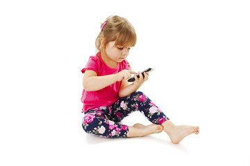 Little girl sitting and sending message on phone mobile. Isolated on white background