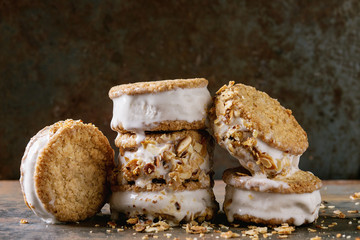 Set of homemade ice cream sandwiches in oat cookies with almond sugar crumbs over dark metal texture background. Close up