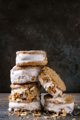 Set of homemade ice cream sandwiches in oat cookies with almond sugar crumbs over dark metal texture background. Close up