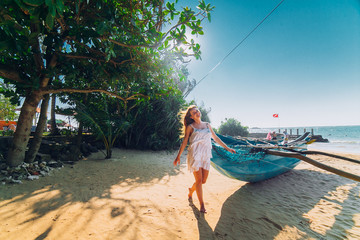 Happy Romantic honeymoon couple on the beach sitting on the sand near old fishing boat and looking each other kissing. Husband with his wife near the ocean. Sri lanka. Hikkaduwa.