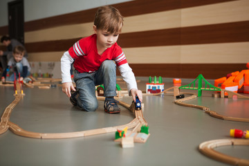 Child boy play with wooden train, build toy railroad  or daycare.