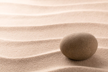 Fototapeta na wymiar Round stone on beach sand. Zen meditation cocept for relaxating and concentration or spa wellness theme for purity and balance. Background with copy space.