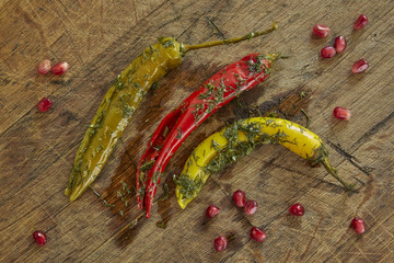 Organic, fresh, green, red and yellow paprikas with pomegranate on a wooden table. Overhead, top view.