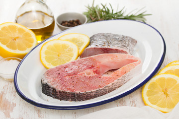 raw fish with lemon on dish on wooden background