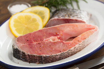 raw fish with lemon on dish on brown background