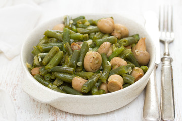 green beans with mushrooms in dish on wooden background