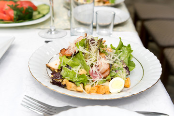 Caesar salad with fried meat, bacon, egg, croutons and lettuce leaves.