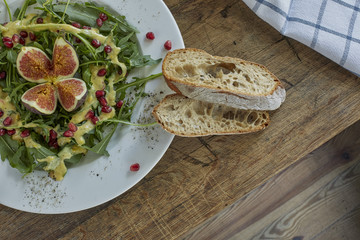 Fresh figs and pomegranate in arugula salad. Overhead, top view.
