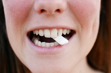 Beautiful woman is brushing her teeth and chewing gum.