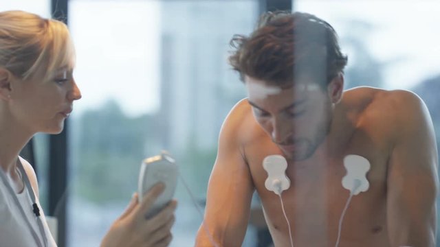  Male athlete on exercise bike being tested and monitored by sports scientist. 