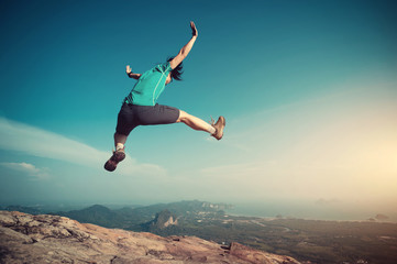 Obraz premium successful woman jumping on rocky mountain peak, freedom, risk, challenge, success concept