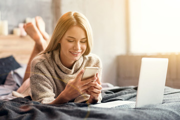 Smiling young woman using technologies at home