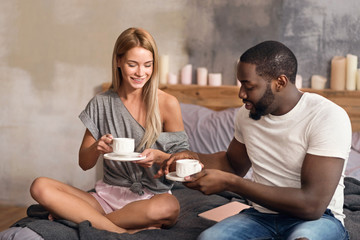Delighted international couple drinking tea at home
