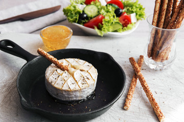 Baked camembert cheese in a frying pan salad