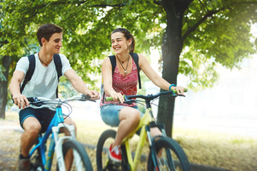 Young people, couple with bicycles in the park. A loving couple on a date on a summer evening. The guy with the girl hugs and kisses. Youth, first feelings, first love, first dates © vitaliymateha