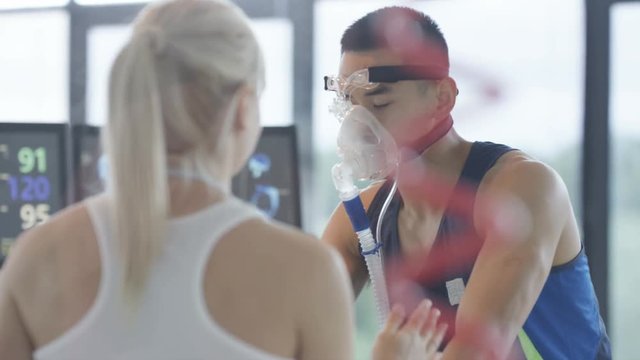  Sports professional analyzing man's fitness levels with hi tech equipment. Professional athlete in training, personal trainer at the gym or scientific research concept. 