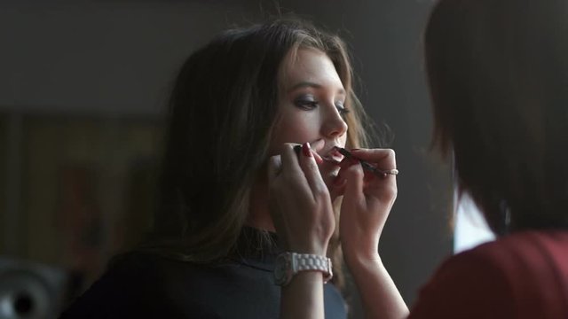 Specialist doing makeup for model. Gentle make-up for the young girl.