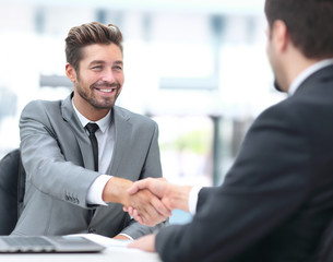 Fototapeta premium Two business people shaking hands and looking at each other with