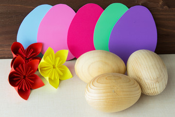 Decorative elements for decorating the house for the Easter holiday. Wooden egg and flowers made of paper. Horizontal. Selective focus.