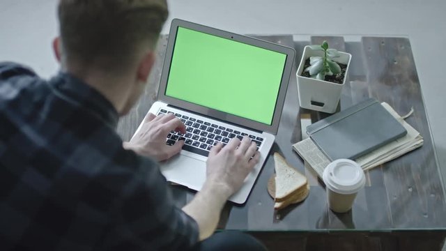High angle view of man typing on laptop with chroma key screen