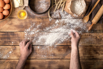 Males hands sprinkle with flour wooden table for making dough