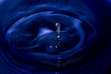 Water drop in dark blue texture color flying from above
