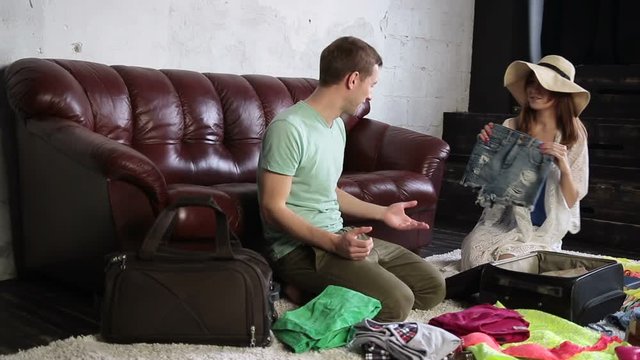 Cheerful couple packing travel bag at home