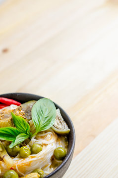 Rice noodles in chicken curry sauce with vegetables on wooden background