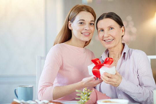 Two happy women holding package with gift