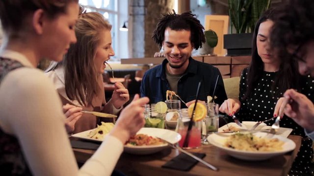 happy friends eating and drinking at restaurant