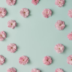 Obraz na płótnie Canvas Pink flower pattern on blue pastel background. Minimal spring concept. Flat lay.