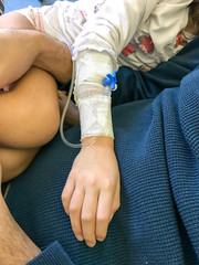 Fototapeta premium Baby girl in hospital bed sleeping on father's chest. Arm detail