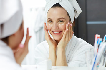 Young woman pampering cream or gel on eye zone