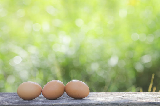Egg on wooden table with shallow DOF green background.