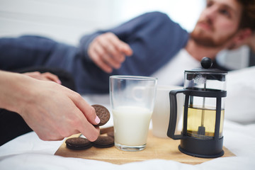 Human hand taking chocolate biscuit sandwich from wooden tray